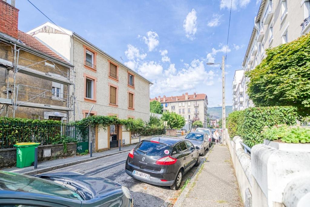 a row of cars parked on a city street at 2 pièces tout confort, déco moderne, wifi fibre in Grenoble