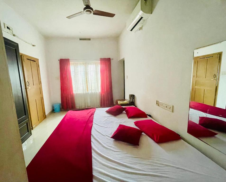 a bedroom with a large white bed with red pillows at Rose Garden home stay Thrissur in Trichūr