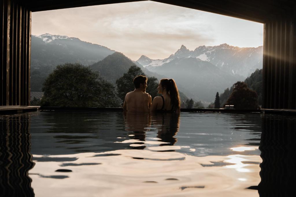 un homme et une femme assis dans une piscine à l'eau dans l'établissement Amrai Suites, à Schruns