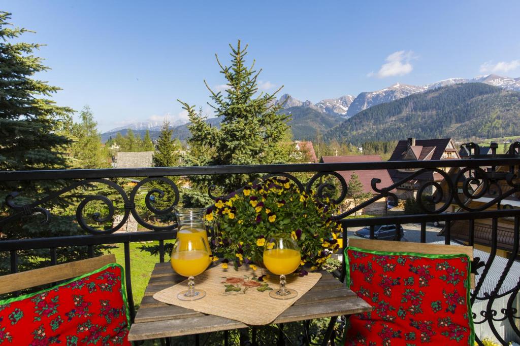 two glasses of orange juice on a table on a balcony at Willa Krzesanica in Kościelisko