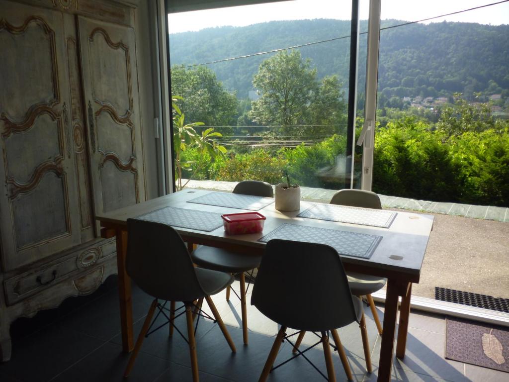 uma mesa e cadeiras num quarto com uma grande janela em T1 Cosy avec Terrasse privée vue Loire dans Maison em Aurec-sur-Loire