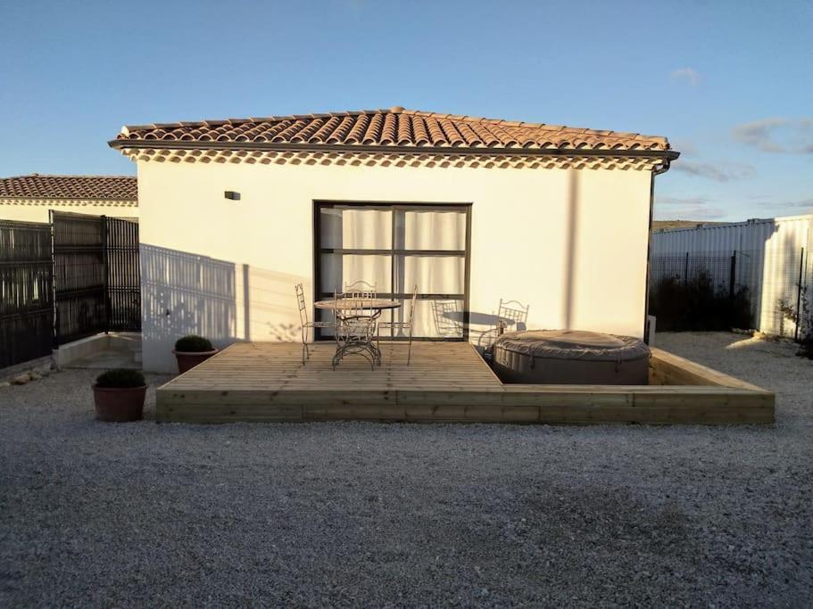 une terrasse en face d'une maison avec une table dans l'établissement Mini villa 84 sur la route des vins, à Sainte-Cécile-les-Vignes