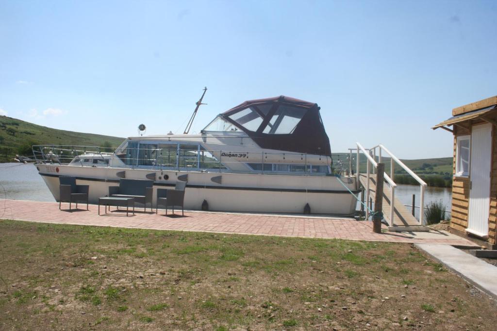 a boat docked at a dock next to a house at The Rose - 37ft Lakeside Yacht with Hot Tub in Swansea