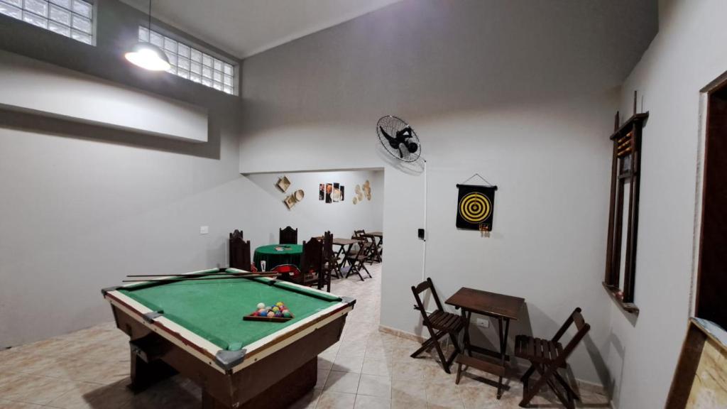 een kamer met een pooltafel en een kamer met stoelen bij Recanto Do Sol Bertioga in Bertioga
