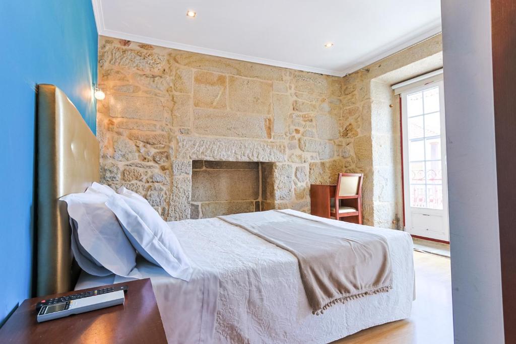 a bedroom with a bed and a stone wall at Alojamento Central in Chaves