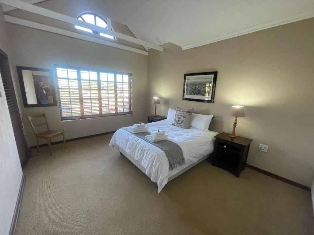 a bedroom with a large white bed and a window at DullVino Apartment @ Millers Cove in Dullstroom