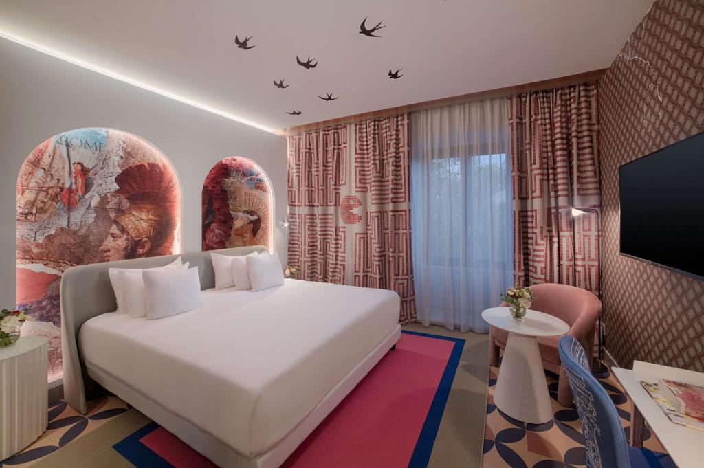 a hotel room with a white bed and a tv at NH Collection Roma Vittorio Veneto in Rome