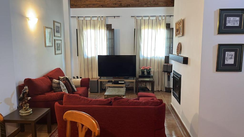 sala de estar con sofá rojo y TV en Aneto Dúplex en Badaguas, en Badaguás