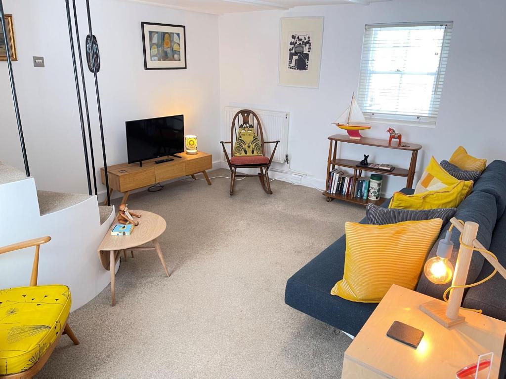 a living room with a blue couch and a tv at Sixpence Cottage, a few steps from the harbour! in St Ives