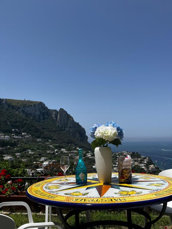 a table with a glass of wine and flowers on it at Suite Apartment con Giardino in Piazzetta in Capri