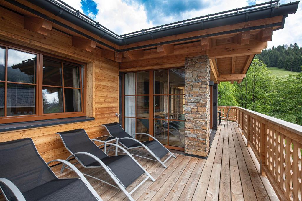 eine Veranda mit Stühlen auf einer Holzterrasse in der Unterkunft Dachstein Chalet in Russbach am Pass Gschütt