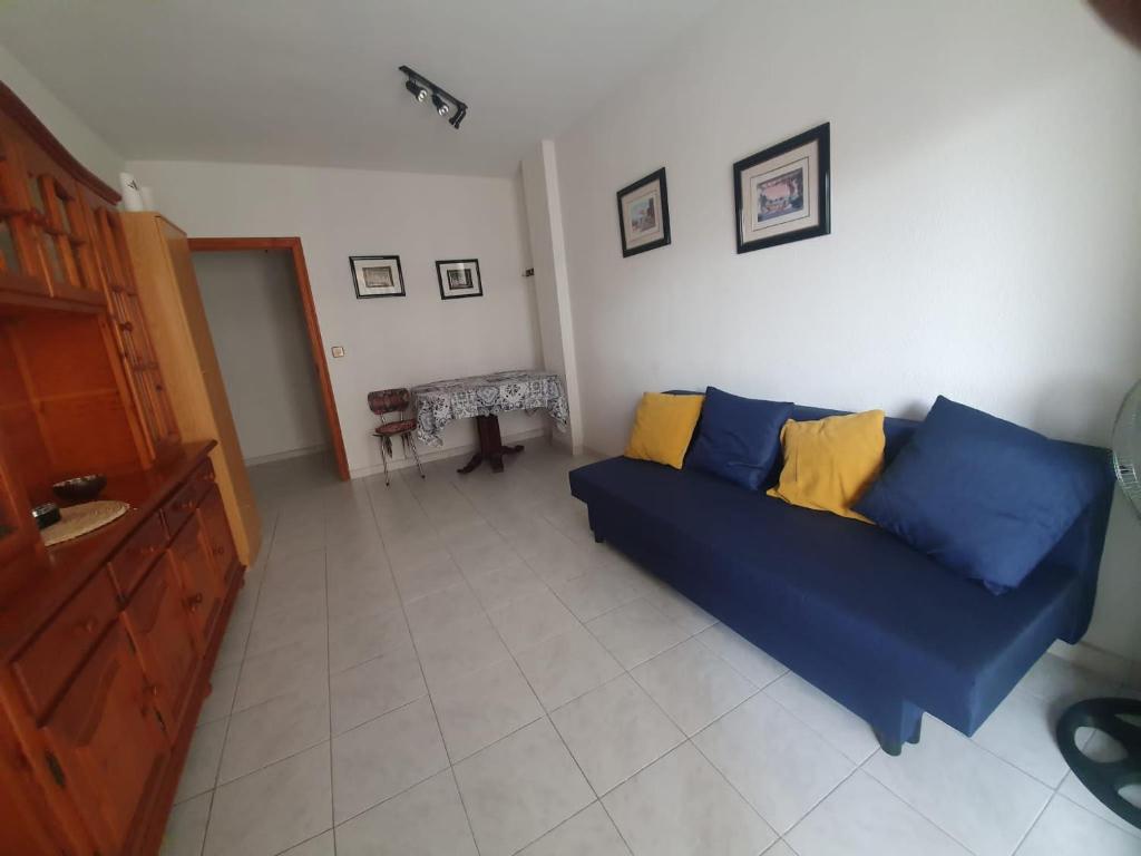sala de estar con sofá azul y almohadas amarillas en Marina Apartments - Playas, en Santa Pola