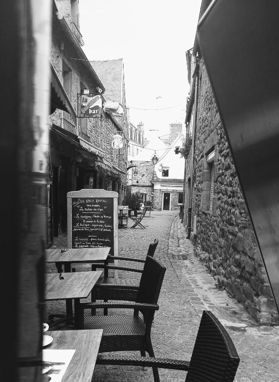 une photo en noir et blanc de bancs et de tables dans une rue dans l'établissement Duplex au lin, à Saint-Pol-de-Léon