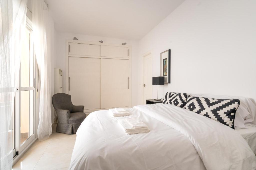 - une chambre blanche avec un lit blanc et une chaise dans l'établissement 29 Close to the beach, 2 bedroom Sabinillas Manilva Andalusia, à San Luis de Sabinillas