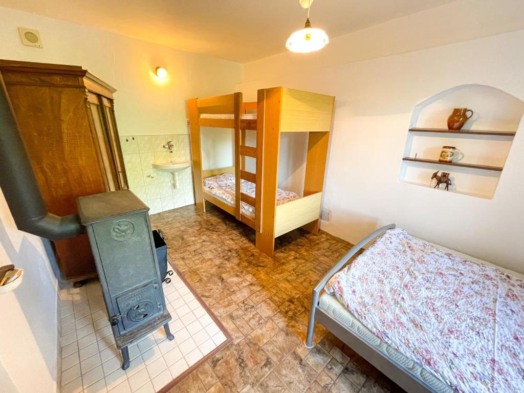 a small room with a bunk bed and a stove at Potvorovská chalupa in Potvorov