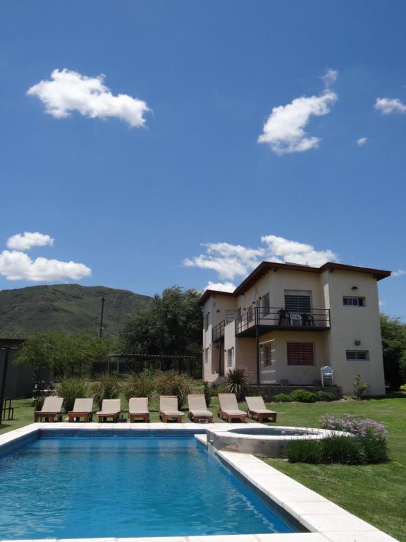 a swimming pool with chairs and a house at El algarrobo escondido in La Falda