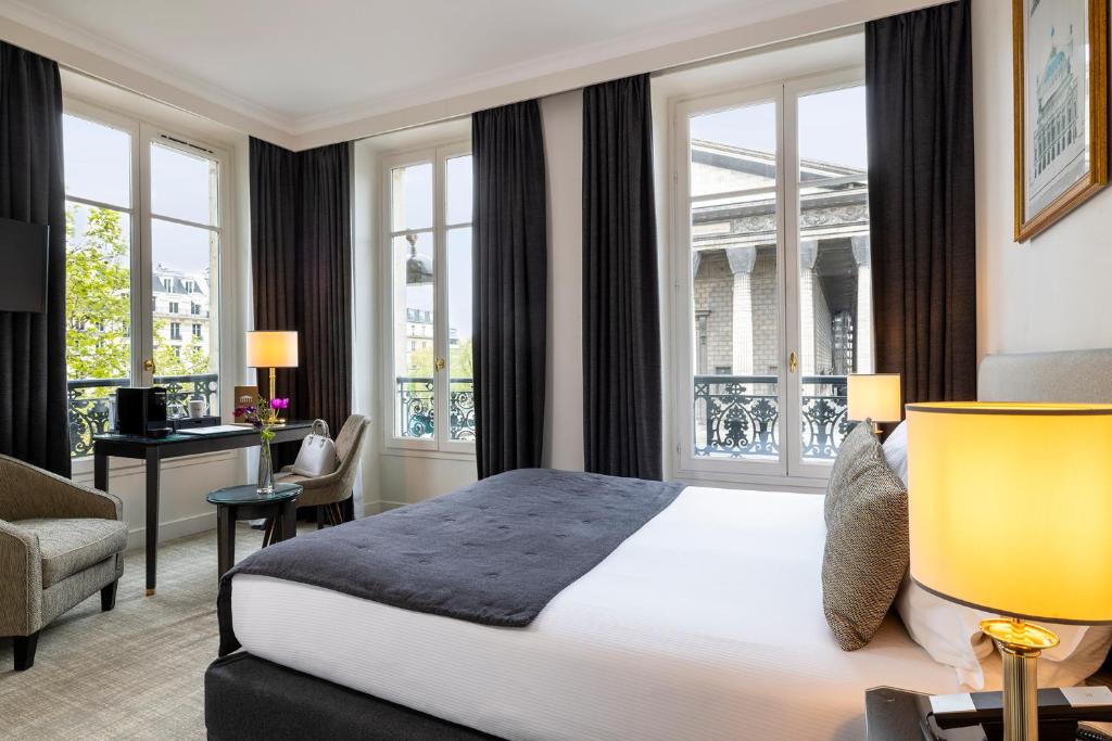 a hotel room with a bed and a desk and windows at Hôtel Madeleine Plaza in Paris