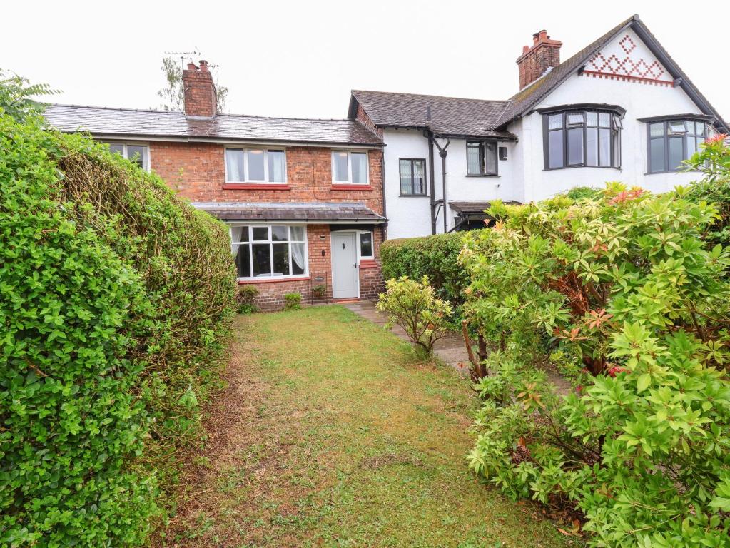 a large white house with bushes in front of it at Gables Cottage in Northwich