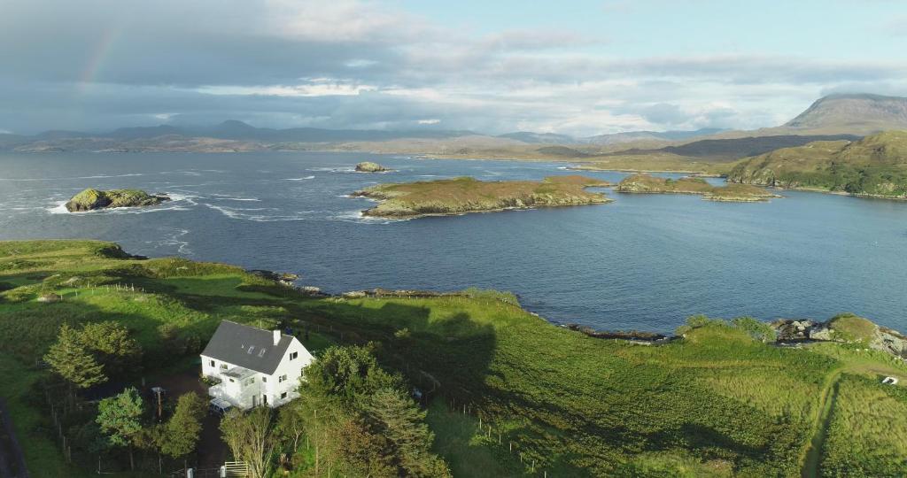 an island in a body of water with a house at Tor Druim in Drumbeg