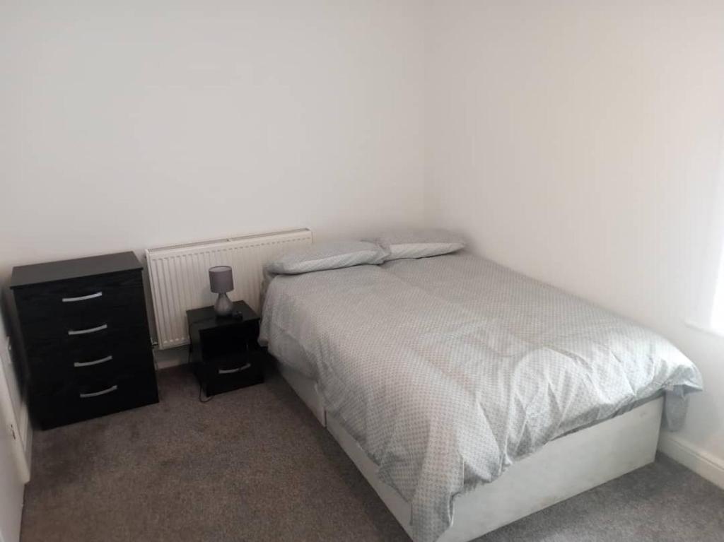 een slaapkamer met een bed en een dressoir met een nachtkastje bij Ensuite Double-bed (E3) close to Burnley city centre in Burnley