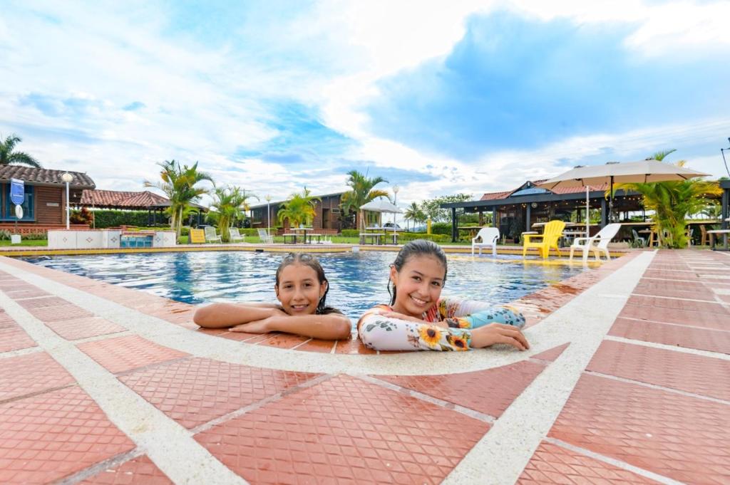 two little girls laying on the edge of a swimming pool at Cabitat Cabañas in Quimbaya