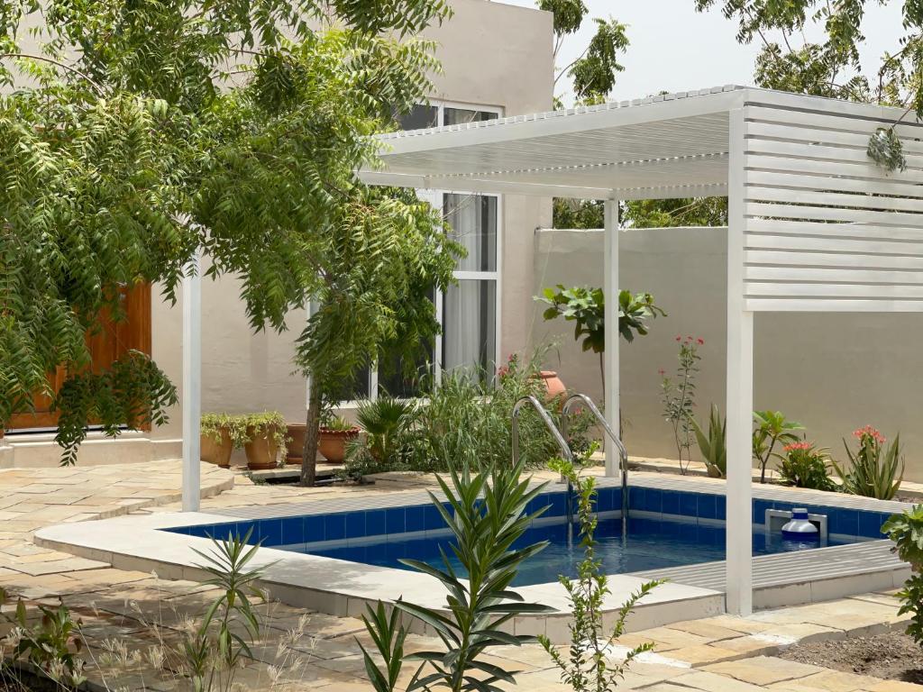 a house with a swimming pool and a pergola at Little Garden private pool villa in Al Ḩamrāʼ