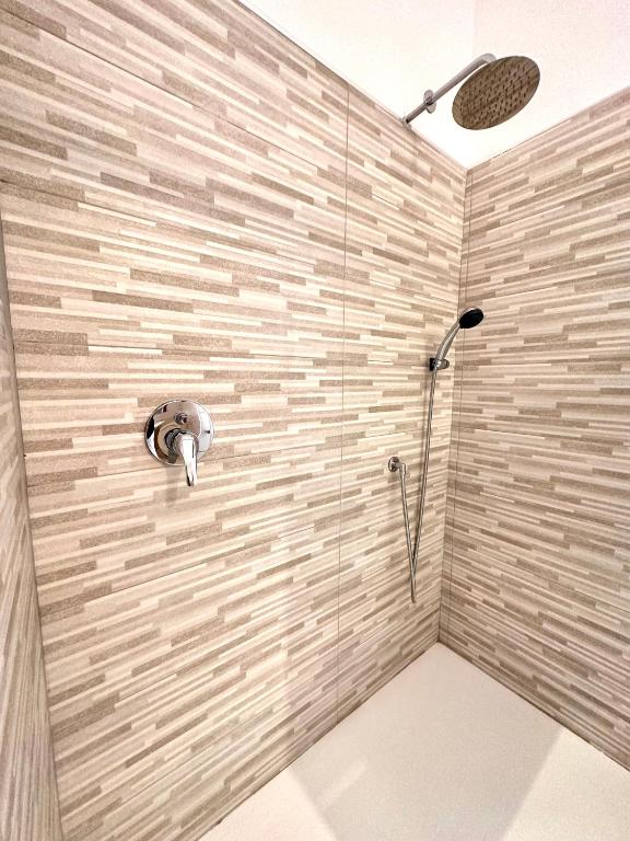 a shower in a bathroom with a stone wall at Double A Luxury Room in Olbia