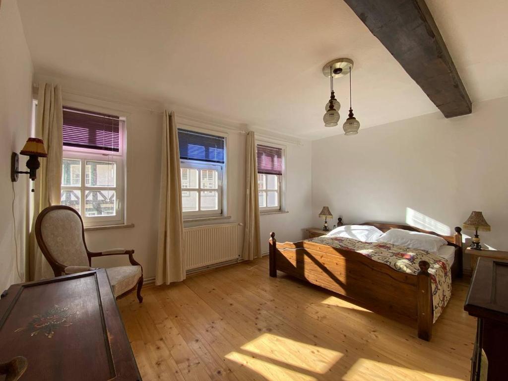a bedroom with a bed and a chair and windows at Haus Anastasia in Stolberg