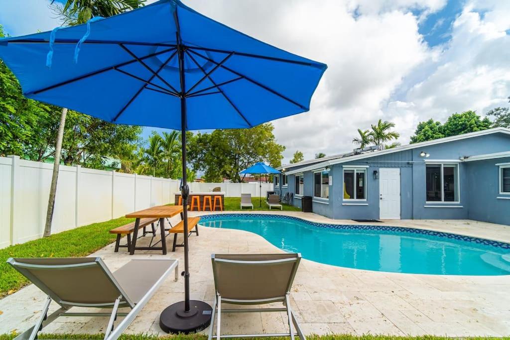 - un parasol bleu et des chaises à côté de la piscine dans l'établissement Vacation Home 3 Bedrooms, Private Pool and Pool Table, à Fort Lauderdale