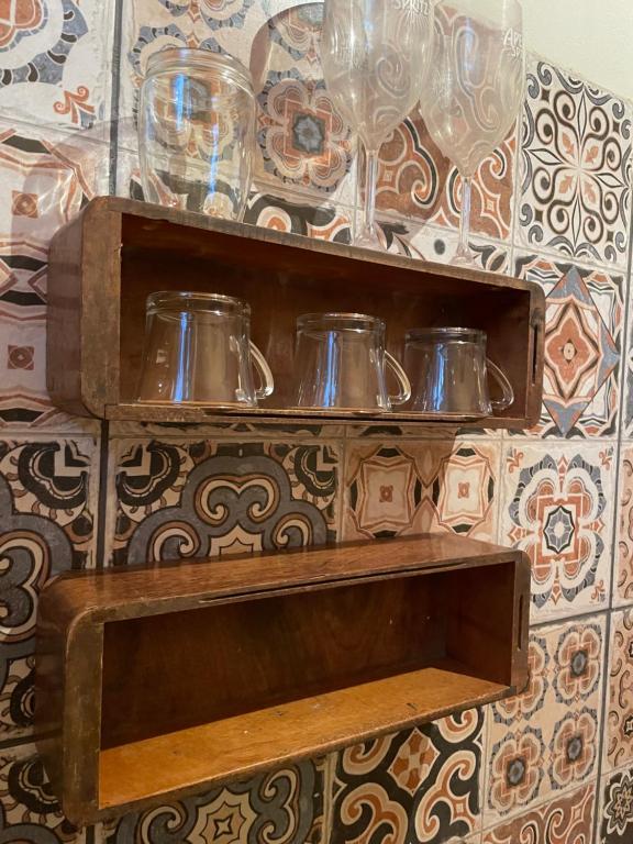 una estantería de madera con tres platos de cristal. en Hospedagem Sabor Da Trilha en Vale do Capao