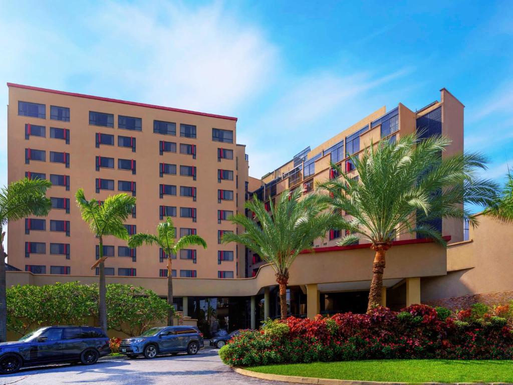 a large building with palm trees in front of it at Mövenpick Hotel Ikoyi Lagos in Lagos