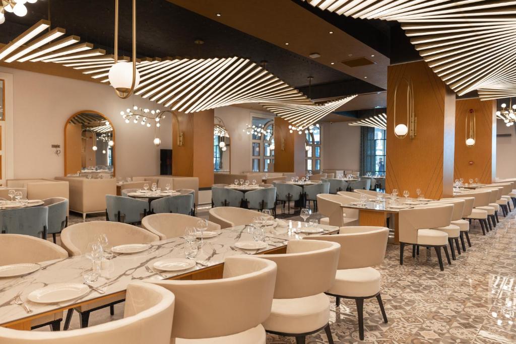 a dining room with tables and chairs and chandeliers at Serenity Queen Hotel in Alanya