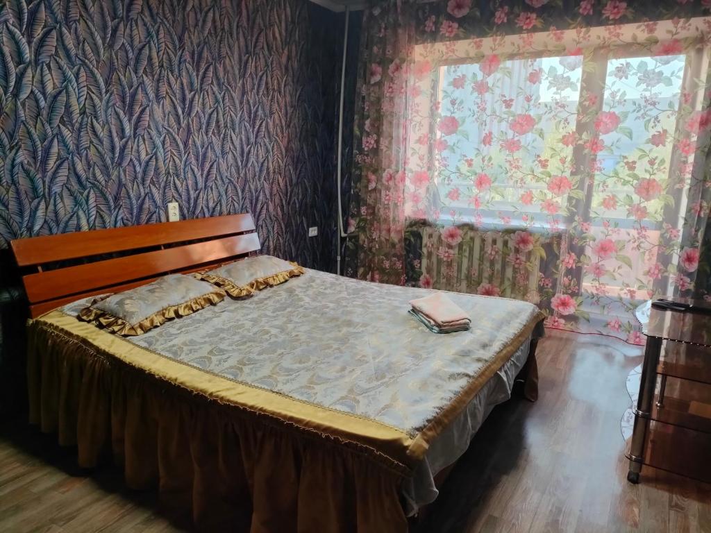 - une chambre avec un lit dans une pièce ornée de papier peint floral dans l'établissement Glinki 33 Apartments, à Semey