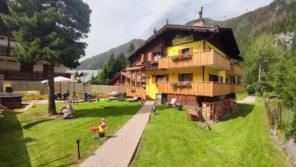 un gran edificio amarillo con un parque infantil delante de él en Villa L'Aida, en Canazei