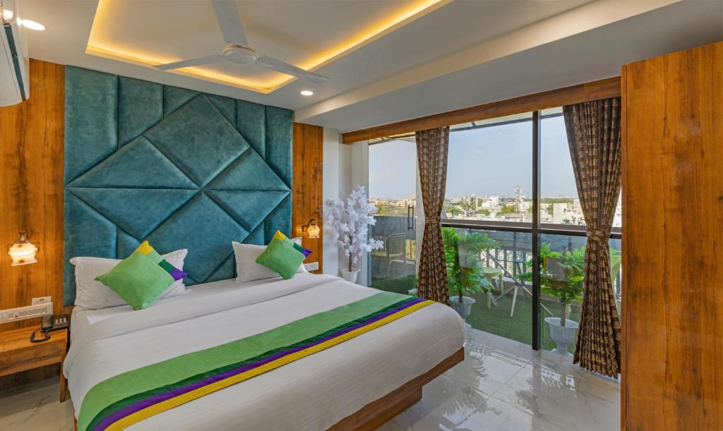 a bedroom with a large bed and a balcony at Treebo Trend Prince Plaza in Ahmedabad