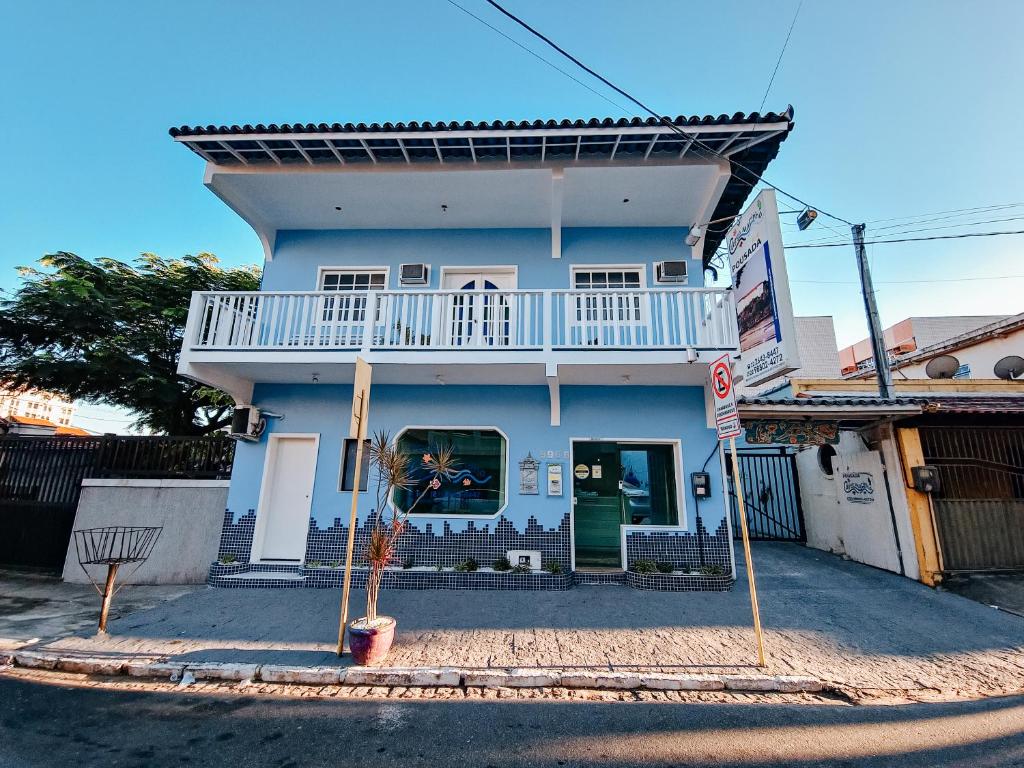 a blue house with a balcony on a street at Pousada Água Marinha in Cabo Frio