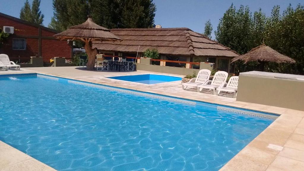 a swimming pool with chairs and a house at Complejo de Cabañas Tierra Nuestra in Mina Clavero