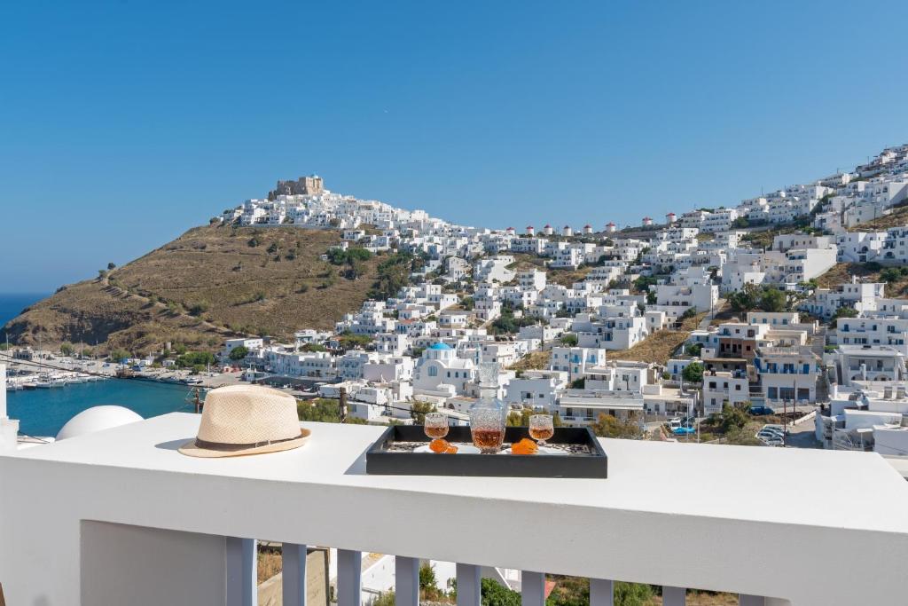 a table with two glasses of wine on a balcony overlooking a city at Korali in Astypalaia Town