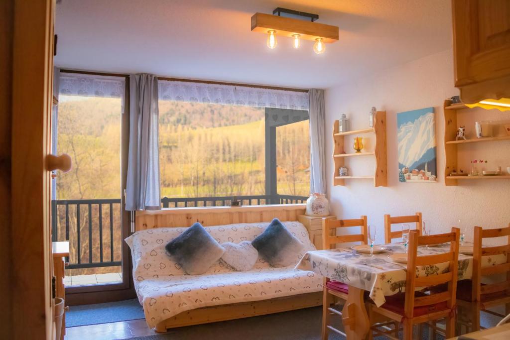 un soggiorno con divano, tavolo e finestra di Le Rossane 26m Balcon vue ad Aillon-le-Jeune