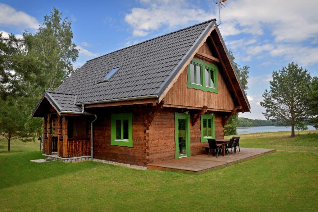 a log cabin with a table and chairs in a yard at Domy Nad Drawskim in Siemczyno