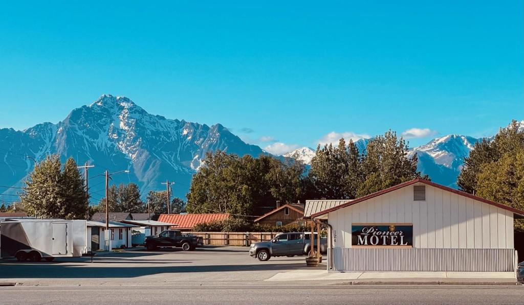 um parque de estacionamento com uma placa de motel em frente a uma montanha em The Pioneer Motel em Palmer