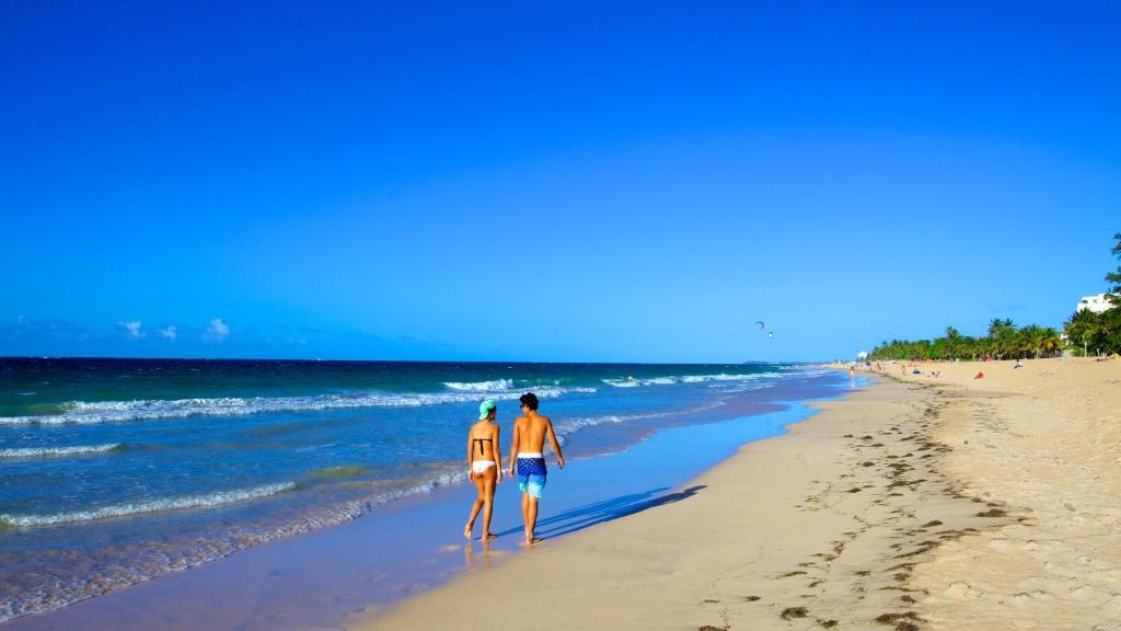 un hombre y una mujer caminando por la playa en 2 bdr beach apartment, generator parking included, en San Juan