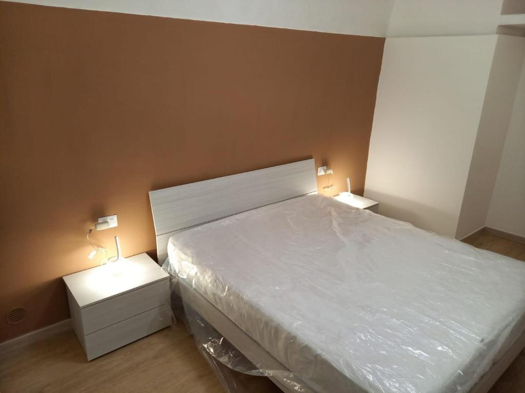 een slaapkamer met een wit bed en 2 nachtkastjes bij CASA VACANZE IL FONDACO in Giovinazzo