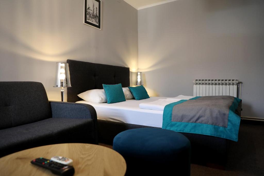 サラエボにあるホテル ソカクのベッド、ソファ、テーブルが備わるホテルルームです。