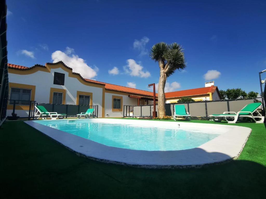 a swimming pool in front of a house with a palm tree at Quinta São José da Relva in Ponta Delgada