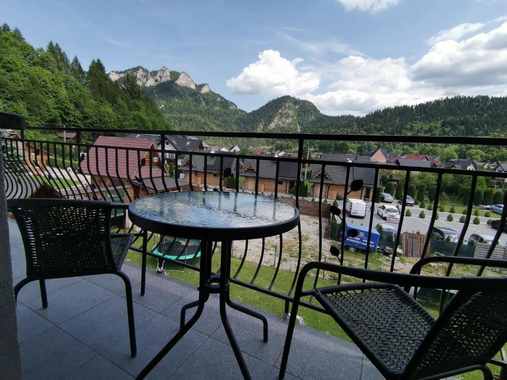 a balcony with two tables and chairs and mountains at Noclegi na Wygonie in Sromowce Niżne