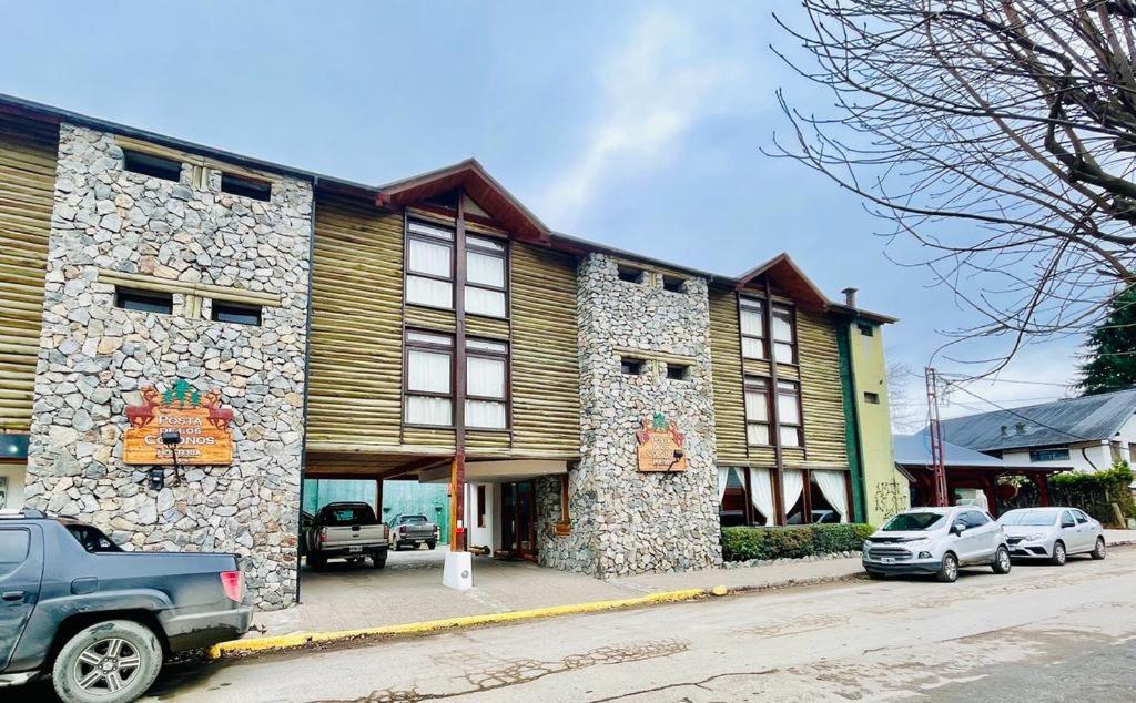 un edificio de piedra con coches estacionados frente a él en Hosteria Posta de los Colonos en Villa La Angostura