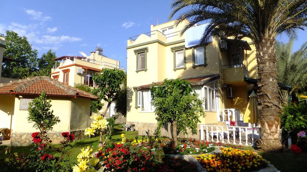 una casa amarilla con una palmera y flores en Konakli Beach Villa, en Konaklı