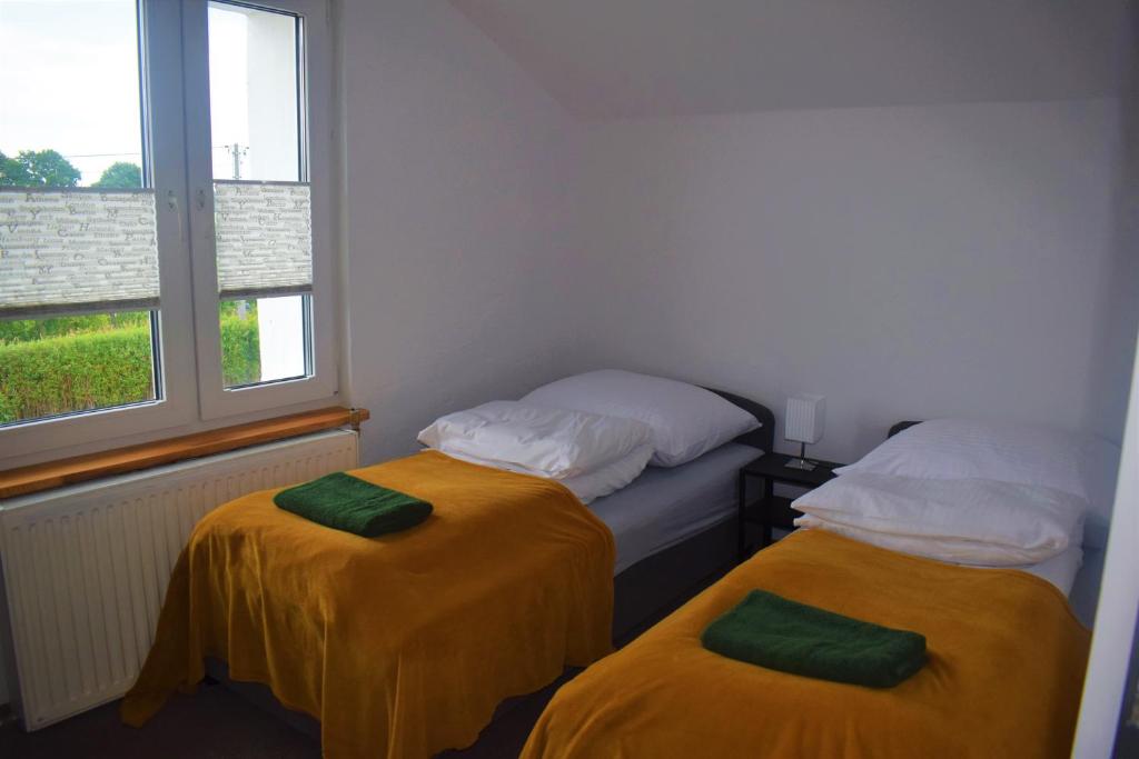 two twin beds in a room with a window at Dobre Wakacje, 8 km od Mielna i od Koszalina in Będzino