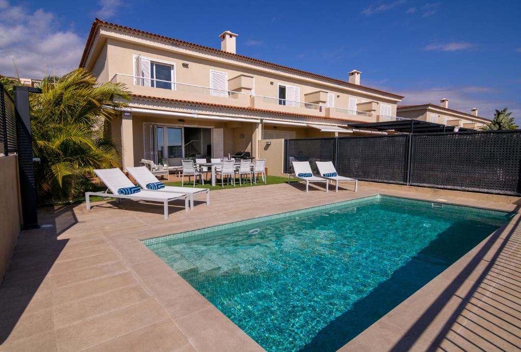 a villa with a swimming pool in front of a house at Oasis del Mar in Puerto de Santiago